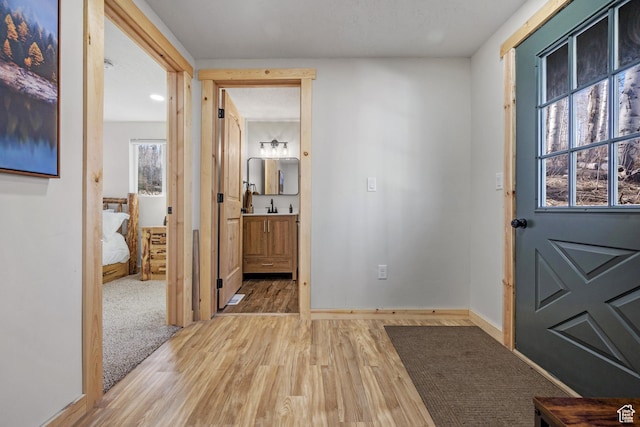 doorway with light wood-style floors, baseboards, and a sink