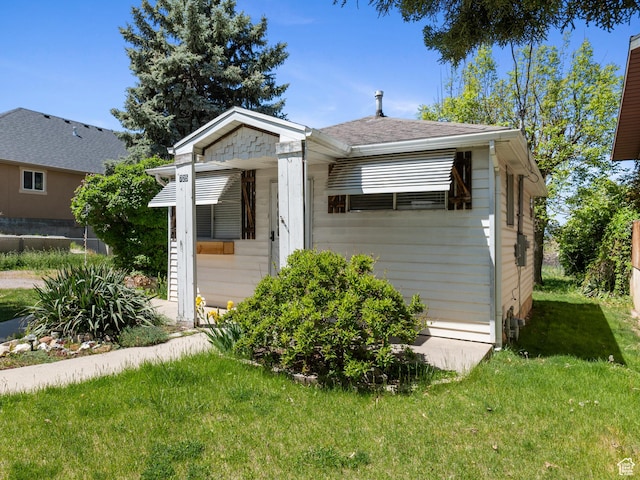 view of front of house featuring a front lawn and a shingled roof