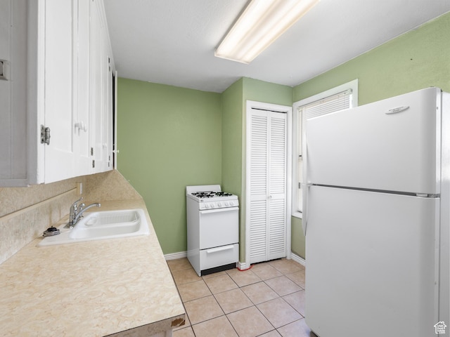 kitchen with white appliances, a sink, light countertops, and white cabinets