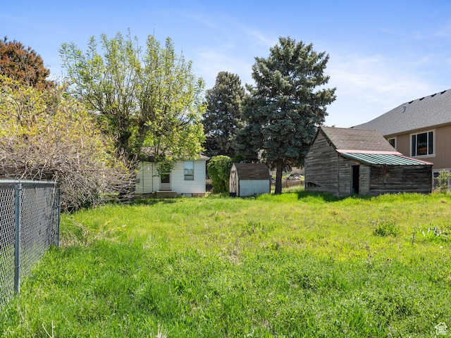 view of yard with a shed, fence, and an outbuilding