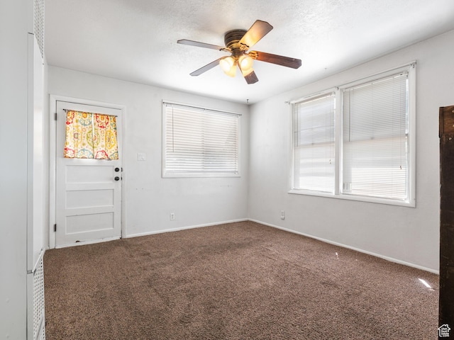carpeted spare room featuring a ceiling fan and baseboards