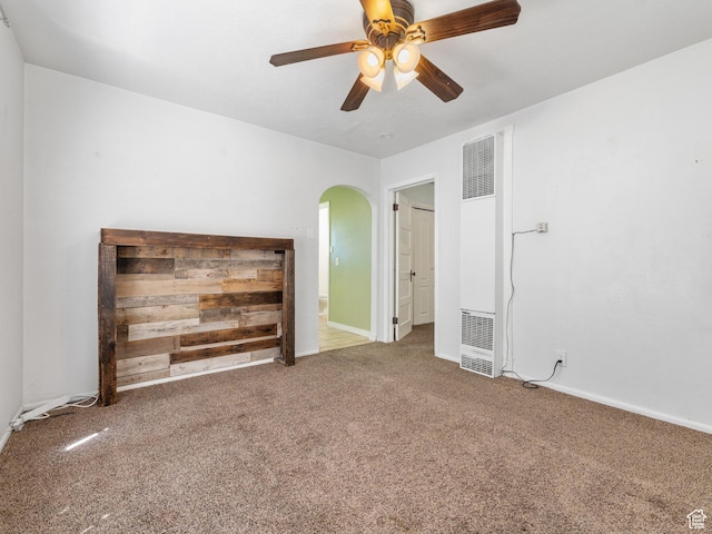 unfurnished living room featuring a heating unit, arched walkways, carpet floors, a ceiling fan, and baseboards