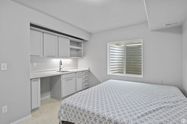 bedroom with a sink, dark aggregate flooring, and baseboards