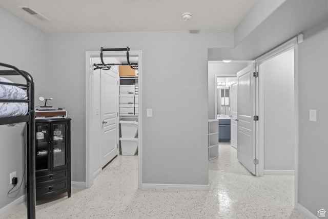 bedroom with a spacious closet, baseboards, and connected bathroom