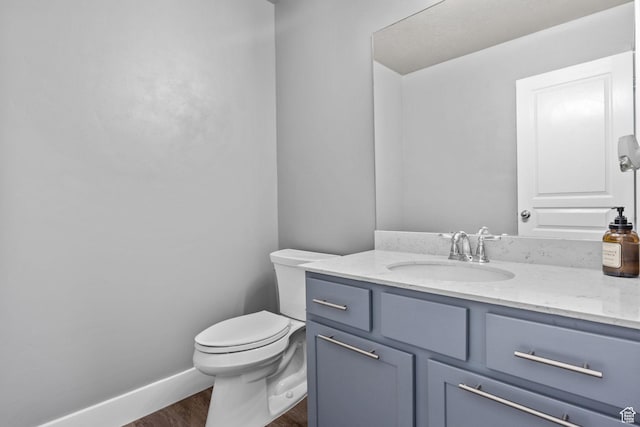 bathroom with wood finished floors, toilet, vanity, and baseboards