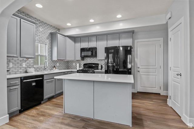 kitchen featuring black appliances, gray cabinets, a sink, light countertops, and tasteful backsplash