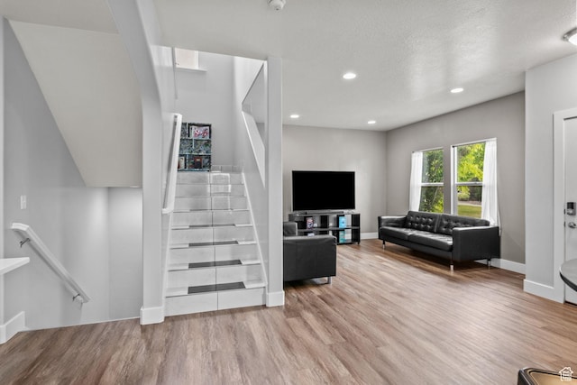 living room featuring wood finished floors, recessed lighting, baseboards, and stairway