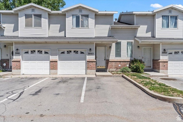 view of property featuring brick siding, an attached garage, and asphalt driveway