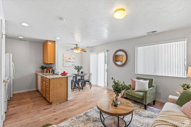 living room featuring light wood-style flooring, a ceiling fan, a textured ceiling, baseboards, and recessed lighting