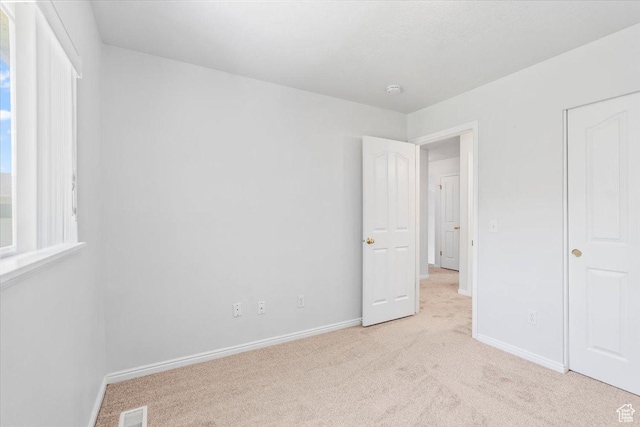 unfurnished bedroom featuring light carpet and baseboards
