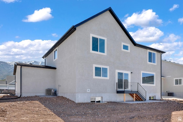 rear view of house with central AC and stucco siding