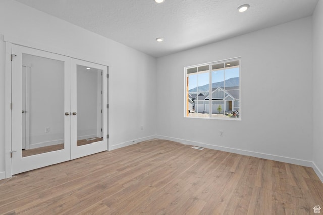 unfurnished room with light wood-style floors, french doors, recessed lighting, and baseboards