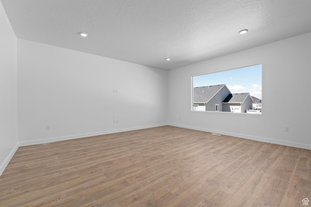 unfurnished room with wood finished floors, baseboards, a textured ceiling, and recessed lighting