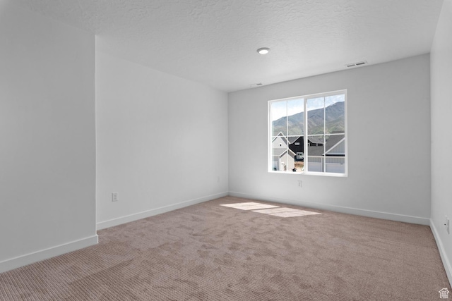 carpeted empty room featuring baseboards and a textured ceiling