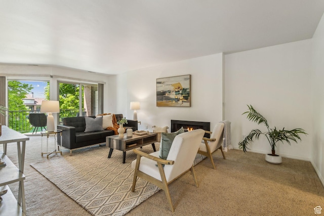 living room featuring a warm lit fireplace and light carpet