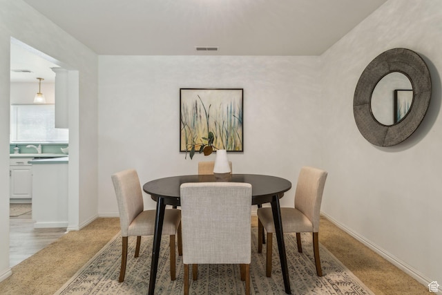dining space with light carpet and baseboards
