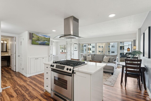 kitchen with stainless steel gas stove, island exhaust hood, wood finished floors, a kitchen island, and recessed lighting