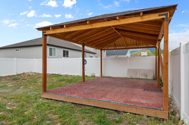 fenced backyard featuring a carport, a wooden deck, and a gazebo