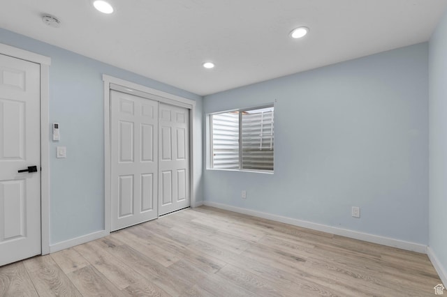 unfurnished bedroom with light wood finished floors, baseboards, recessed lighting, and a closet