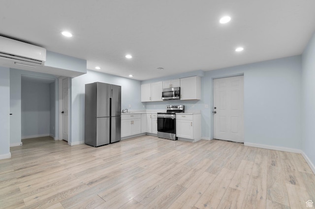 kitchen featuring appliances with stainless steel finishes, a wall mounted AC, light countertops, baseboards, and white cabinets