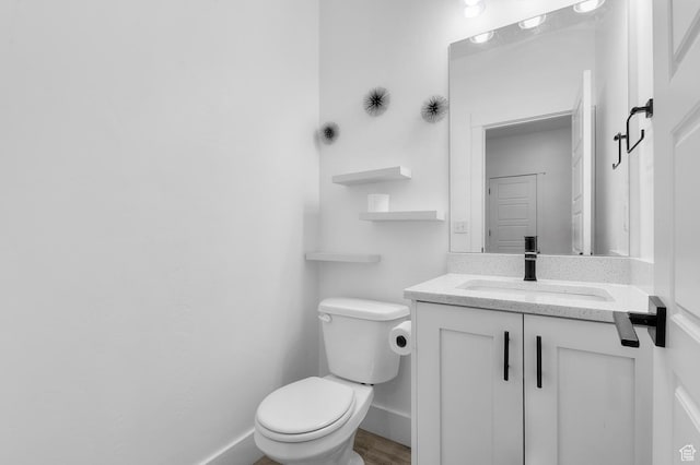 bathroom with toilet, vanity, and baseboards