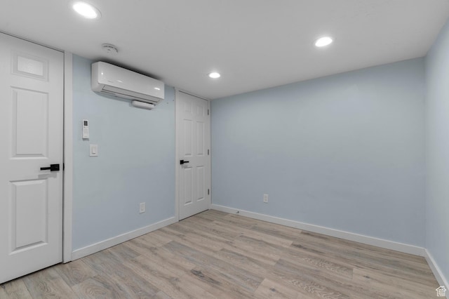 empty room featuring a wall mounted air conditioner, baseboards, light wood-style flooring, recessed lighting, and a smoke detector