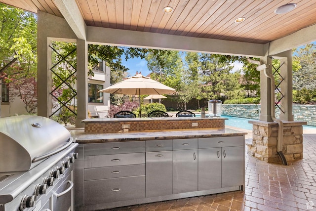 view of patio with area for grilling, an outdoor pool, mail area, and exterior kitchen