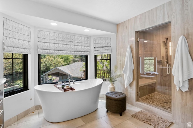 bathroom with healthy amount of natural light, a shower stall, tile patterned floors, a freestanding tub, and recessed lighting
