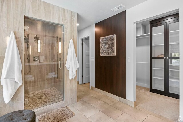 full bathroom with a stall shower, baseboards, tile patterned flooring, and a walk in closet