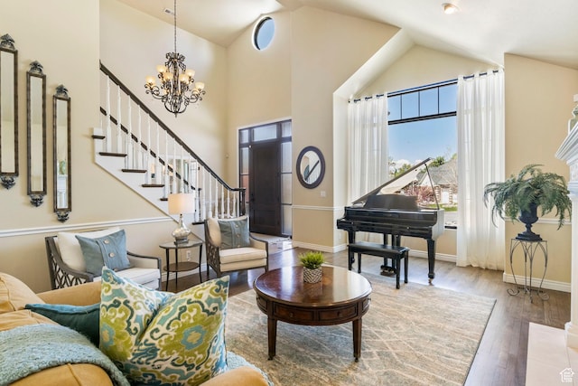 sitting room featuring a chandelier, wood finished floors, stairway, baseboards, and high vaulted ceiling