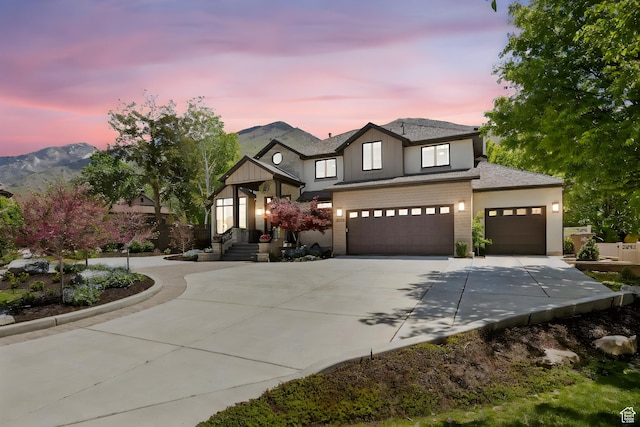 view of front of house with concrete driveway, a garage, a shingled roof, and a mountain view