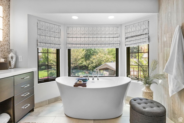 bathroom with a soaking tub, tile patterned flooring, vanity, and baseboards