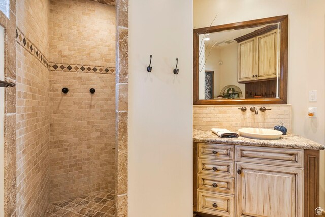 full bath featuring a tile shower, decorative backsplash, and vanity
