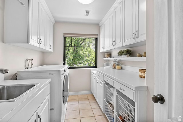 clothes washing area featuring cabinet space, washing machine and dryer, baseboards, and light tile patterned floors
