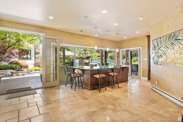 indoor wet bar featuring french doors, recessed lighting, a baseboard radiator, stone tile flooring, and hanging light fixtures