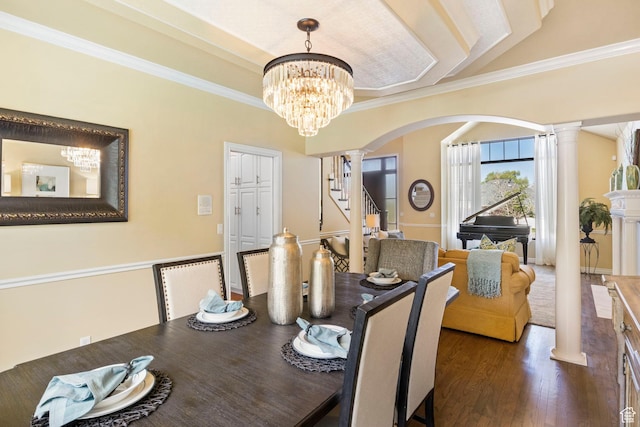 dining room with ornate columns, arched walkways, a chandelier, wood finished floors, and ornamental molding