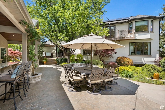 view of patio with a balcony and outdoor dining space