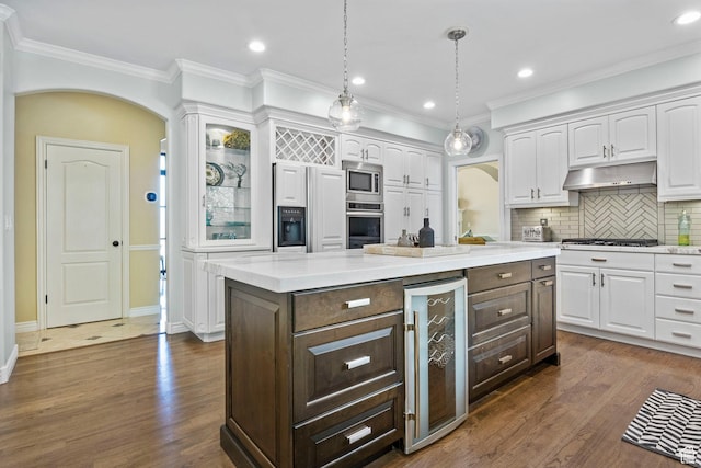 kitchen featuring beverage cooler, appliances with stainless steel finishes, white cabinetry, dark brown cabinetry, and recessed lighting