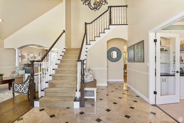 entryway with arched walkways, a high ceiling, stairway, inlaid floor details, and baseboards