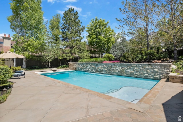 outdoor pool featuring fence and a patio