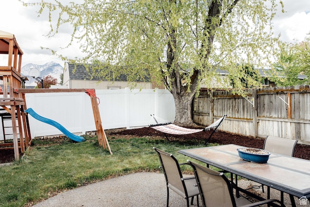 view of patio / terrace featuring outdoor dining area, a playground, and a mountain view