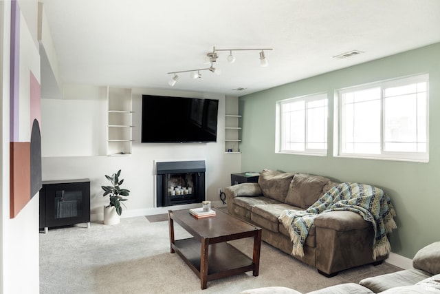 carpeted living room featuring a glass covered fireplace and baseboards