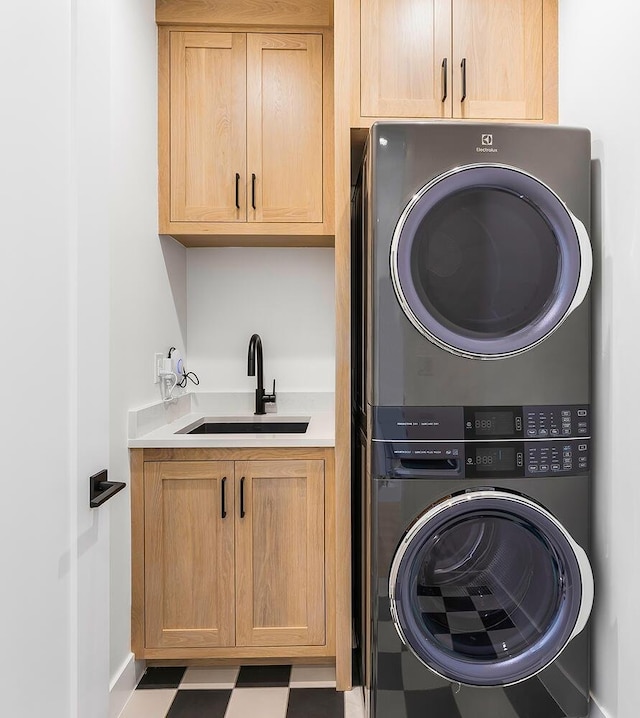 washroom featuring stacked washer and clothes dryer, cabinet space, tile patterned floors, and baseboards