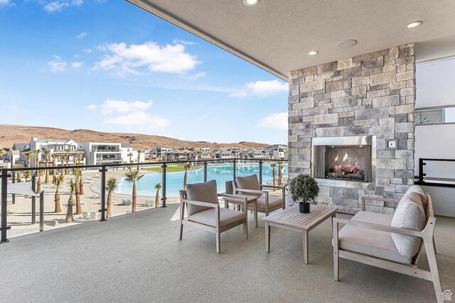 balcony featuring an outdoor stone fireplace, view of pool, and a water and mountain view