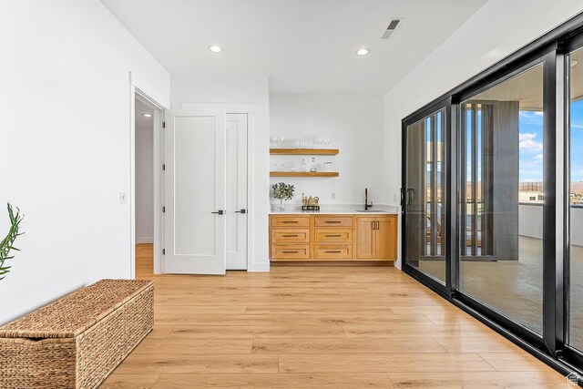 indoor wet bar with light wood finished floors and recessed lighting