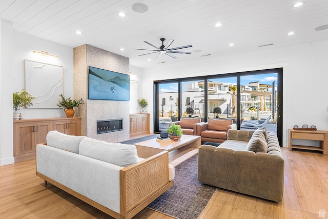 living room featuring wood ceiling, recessed lighting, light wood-style floors, a ceiling fan, and a tile fireplace