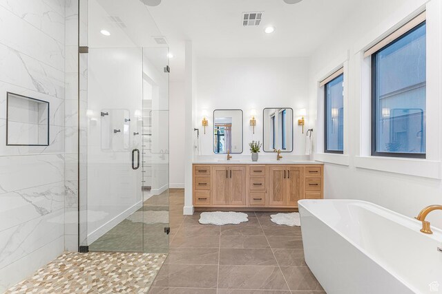 bathroom with a stall shower, double vanity, a freestanding tub, and recessed lighting