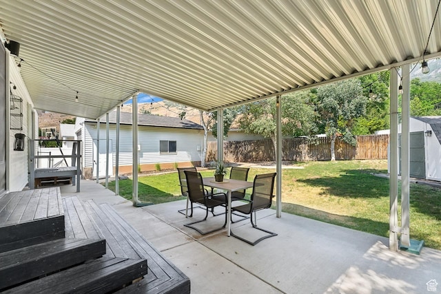 view of patio / terrace featuring an outdoor structure, outdoor dining area, a shed, and a wooden deck