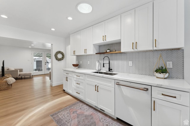 kitchen with white dishwasher, a sink, light wood finished floors, white cabinetry, and backsplash