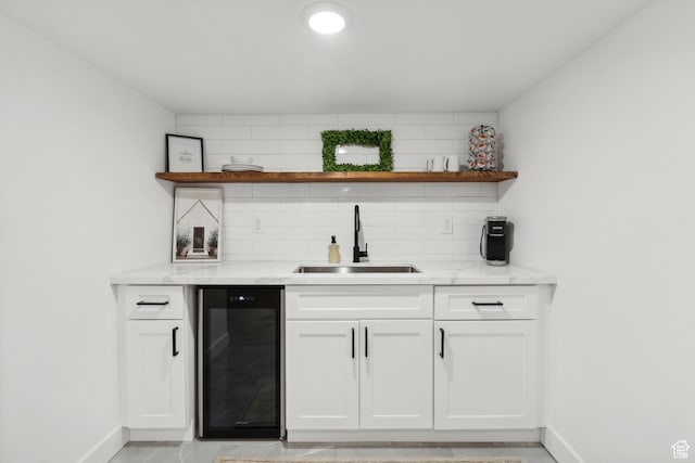 indoor wet bar with beverage cooler, baseboards, and backsplash
